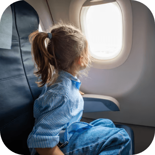 Niña mirando por la ventanilla de un avión durante el vuelo